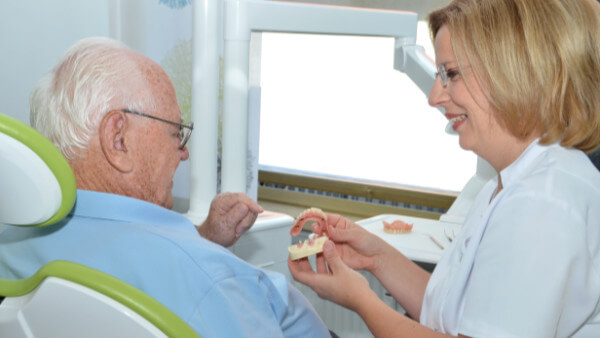 Zahnärztin hält Zahnprothese in der Hand